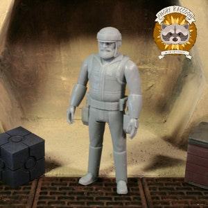 Pode incluir: Uma figura em miniatura cinza de um homem em uniforme, capacete e cinto de ferramentas, em pé em um ambiente detalhado. A figura tem barba e está em uma postura neutra. O logotipo Angry Raccoon Miniatures está no canto superior direito.
