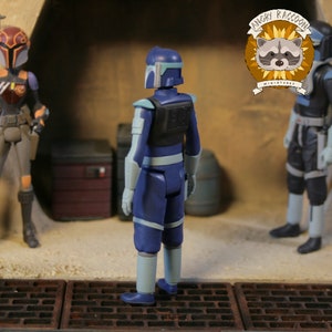 May include: A blue action figure of a character from a science fiction franchise, viewed from the back. The figure has light blue accents on the arms and legs, and a black vest. The figure is standing on a textured surface with other figures in the background.