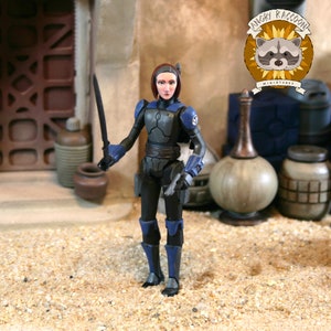 May include: A plastic action figure of a character with short dark hair, wearing black and blue armor with shoulder pauldrons and gauntlets. The figure holds a thin black sword in one hand and stands in a desert-like setting with various containers.