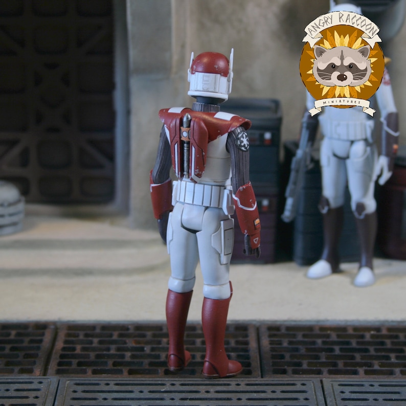 May include: A white and maroon action figure of a soldier wearing a helmet with antennae, a jetpack, and armour plating. The figure features a Galactic Empire symbol on the shoulder and weathered paint details on the helmet and armour components.