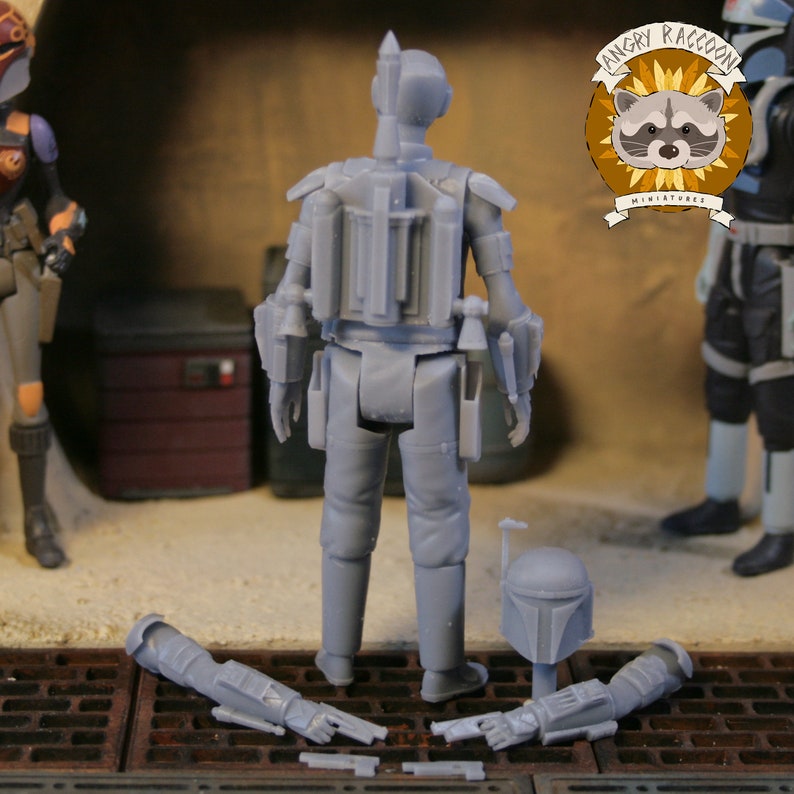 May include: A grey miniature action figure of a character with a helmet and jetpack, with detached arm and weapon components. The figure is standing on a metal grate, with other figures and a logo in the background.