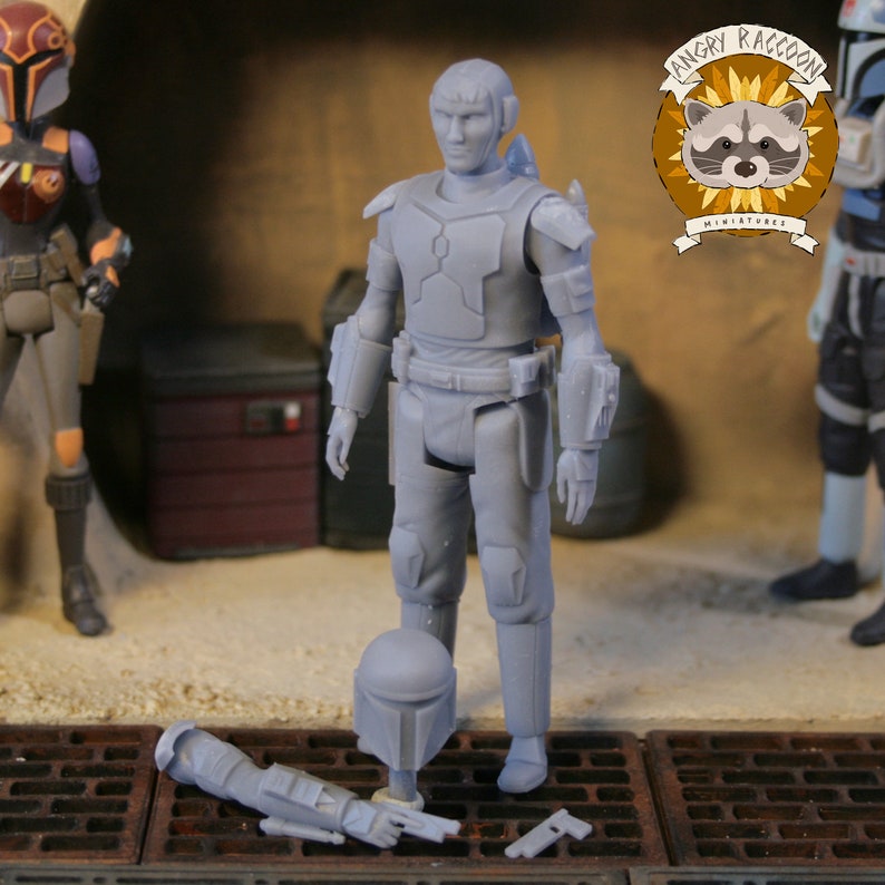 May include: A gray action figure of a character in armor, with a helmet and weapon lying on the ground. The figure is standing on a metal grate. The Angry Raccoon Miniatures logo is in the background.