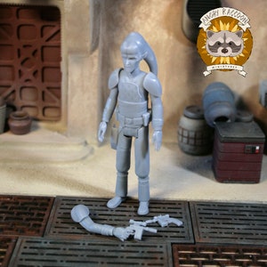 Può includere: Action figure grigia di un alieno umanoide con una lunga coda sulla testa, che indossa un'armatura e una cintura porta attrezzi. La figura è in piedi su una griglia metallica, con un braccio staccato e due blaster nelle vicinanze. Lo sfondo include una facciata di un edificio e il logo "Angry Raccoon Miniatures".