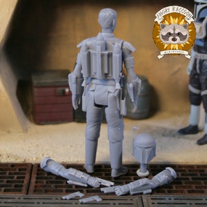 May include: A gray miniature figure of a character from a science fiction franchise, viewed from the back. The figure is wearing armor and has a helmet and detached arms. The Angry Raccoon Miniatures logo is visible in the background.