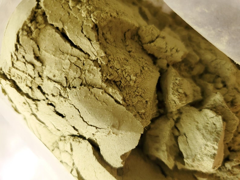 May include: Close-up of a bag of green powder. The powder is finely ground and has a slightly rough texture.