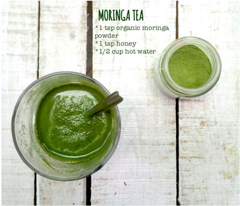 May include: A glass of green moringa tea with a spoon in it, next to a jar of moringa powder. The text on the image reads "MORINGA TEA * 1 tsp organic moringa powder * 1 tsp honey * 1/2 cup hot water"