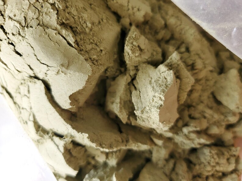 May include: Close-up of a pile of loose, light green powder. The powder is dry and crumbly, with a slightly rough texture.