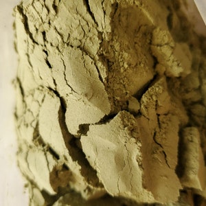 May include: Close-up of a pile of green powder. The powder is finely ground and has a slightly rough texture.