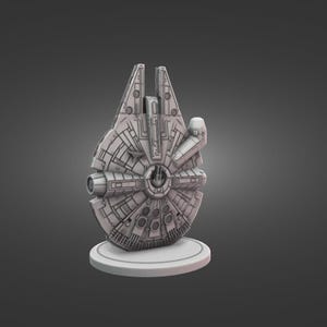Può includere: Un modello grigio dettagliato dell'astronave Millennium Falcon, un'astronave immaginaria del franchise di Star Wars. Il modello è montato su una base circolare bianca, che mostra intricati pannelli e dettagli di design. La forma iconica della nave è chiaramente visibile.