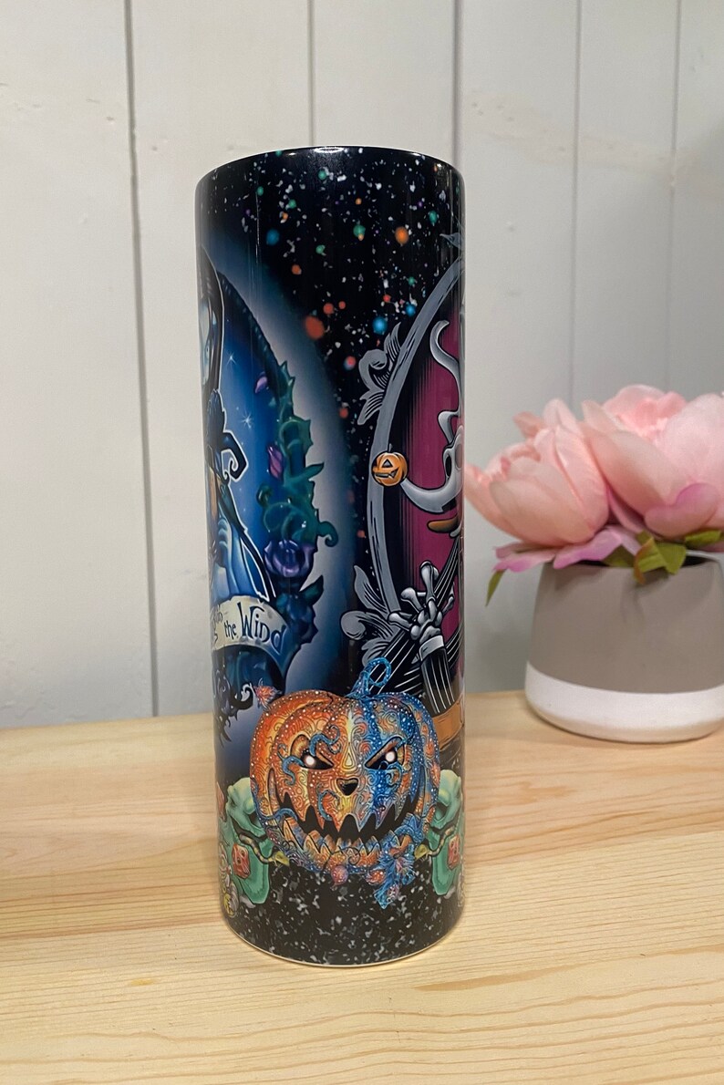 Peut inclure: Un grand gobelet cylindrique avec un motif color&eacute; sur le th&egrave;me d'Halloween. Le gobelet pr&eacute;sente un fond de ciel &eacute;toil&eacute; avec des images de Jack Skellington, Sally et une citrouille fendue. Le texte sur le gobelet se lit "In the Wind".