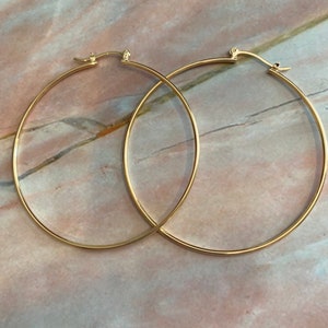 May include: A pair of large, gold hoop earrings. The hoops are thick and have a simple, classic design.