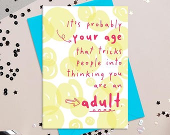 May include: A greeting card with a white background and yellow bubble designs. The card has the text "It's probably your age that tricks people into thinking you are an adult" in pink and black. The card is on a blue envelope.