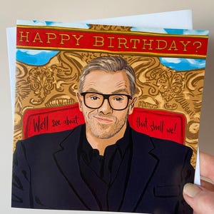 May include: A greeting card featuring a cartoon illustration of a man in glasses and a suit. The card has a red background with gold accents and the text "Happy Birthday? We'll see about that shall we!"