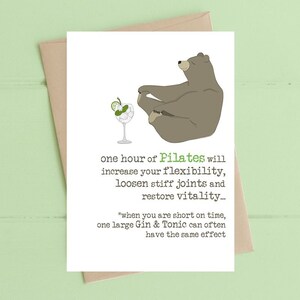 May include: A humorous greeting card with a cartoon bear doing a yoga pose and a glass of gin and tonic. The text reads "one hour of Pilates will increase your flexibility, loosen stiff joints and restore vitality... *when you are short on time, one large Gin & Tonic can often have the same effect"