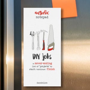 May include: A white magnetic notepad with the text "magnetic notepad" and "DIY jobs" in red. The notepad has a drawing of a hammer, saw, and two wrenches. The text below the drawing says "a never-ending list of 'projects' to start/continue/finish". The bottom of the notepad says "dandelion".