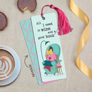 May include: A rectangular bookmark with a light blue grid background, featuring a pink-clad figure reading a book while holding a wine glass in a teal armchair. The text reads, All I need is wine and a good book. It includes a bright pink tassel.