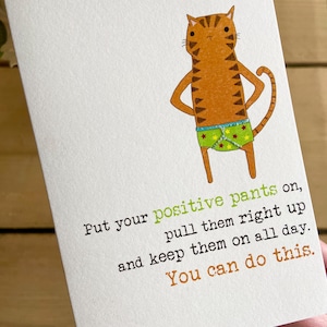 May include: A greeting card with a cartoon cat wearing green and yellow underwear with stars. The text on the card reads "Put your positive pants on, pull them right up and keep them on all day. You can do this."