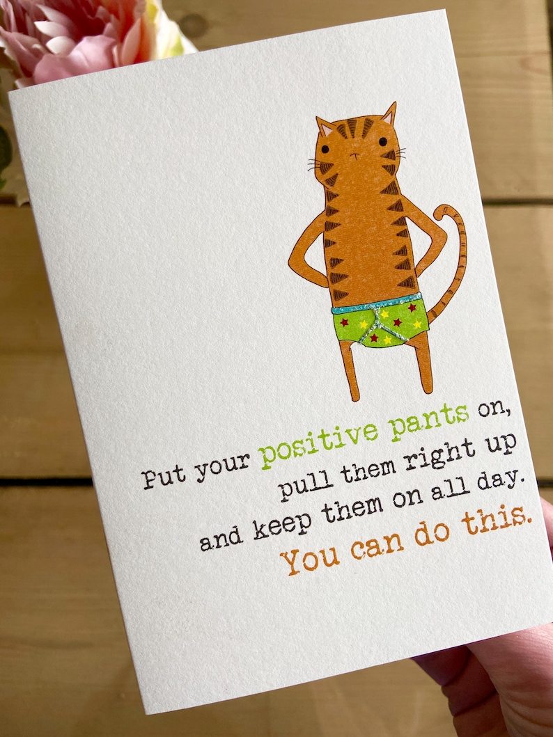 May include: A greeting card with a cartoon cat wearing green and yellow underwear with stars. The text on the card reads "Put your positive pants on, pull them right up and keep them on all day. You can do this."