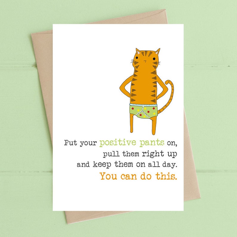 May include: A greeting card with a cartoon cat wearing underwear with stars on it. The text on the card reads: "Put your positive pants on, pull them right up and keep them on all day. You can do this."