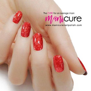 Może przedstawiać: Zbliżenie dłoni z czerwonym lakierem do paznokci z brokatem. Paznokcie są pomalowane błyszczącym czerwonym lakierem. Tekst "The CURE for an average mani manicure www.manicurenailpolish.com" jest widoczny w tle.