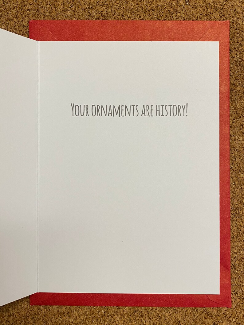 May include: A red card with a white interior. The inside of the card has the text "YOUR ORNAMENTS ARE HISTORY!" printed in black.