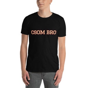 May include: Black t-shirt with the text "CSOM BRO" in yellow with a red outline.
