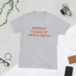 May include: A gray t-shirt with the text "MORRISSEY COLLEGE OF ARTS & CRAFTS" printed in red.