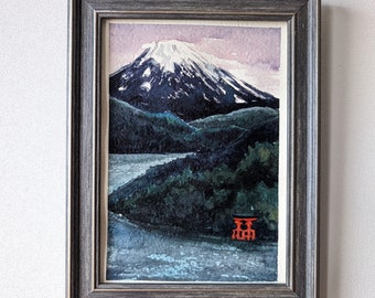 May include: A framed watercolor painting of Mount Fuji with a red torii gate in the foreground. The mountain is snow-capped and the sky is a soft purple.