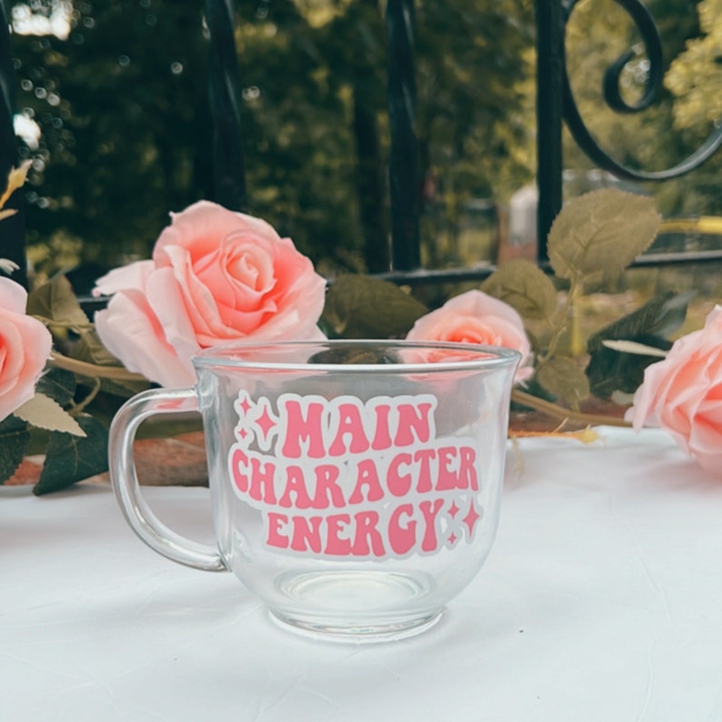 May include: A clear glass mug with a pink and white sticker that says "Main Character Energy".