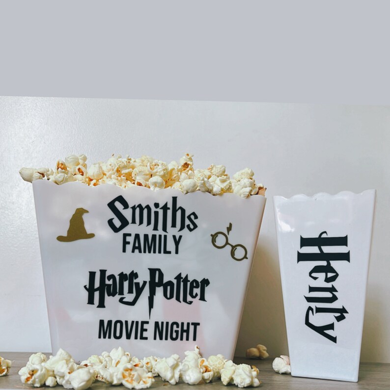 May include: Two white popcorn containers with black text. One container says "Smiths Family Harry Potter Movie Night" and the other says "Henry".