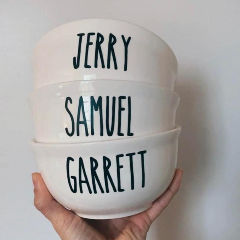 K&ouml;nnte beinhalten: Drei wei&szlig;e Keramikschalen, die &uuml;bereinander gestapelt sind. Die Schalen sind mit den Namen "Jerry", "Samuel" und "Garrett" in schwarzer Schrift personalisiert.