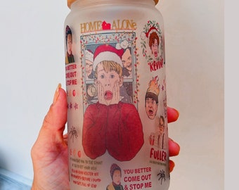 May include: A frosted glass jar with a wooden lid featuring a Home Alone themed design. The jar has a white background with images of characters from the movie, including Kevin McCallister, and text that reads "Home Alone", "You Better Come Out & Stop Me", "Kevin", and "Fuller".