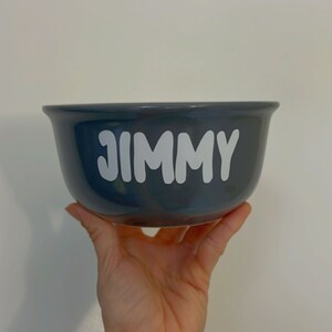 K&ouml;nnte beinhalten: Eine dunkelgraue Keramiksch&uuml;ssel mit dem Namen "JIMMY" in wei&szlig; auf der Vorderseite.