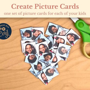 May include: A set of picture cards featuring different children's faces. The cards are arranged in a heart shape on a wooden surface. A pair of green scissors is visible in the top right corner of the image.