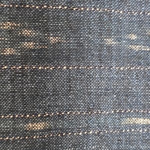Peut inclure: Gros plan sur un tissu bleu foncé avec un motif rayé blanc subtil. Le tissu a une apparence texturée et tissée.