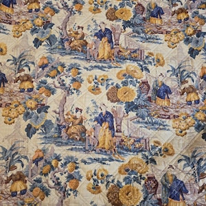Pode incluir: Tecido acolchoado com um padrão repetitivo de figuras em trajes tradicionais, flores e árvores em tons de azul, amarelo e bege. O design tem um padrão de diamante acolchoado.