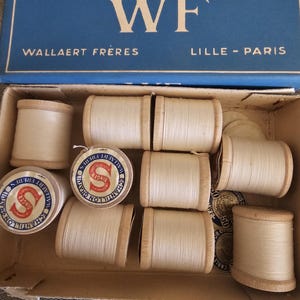 May include: A box of white thread spools labelled "Louis D'Or WF Wallaert Frères Lille - Paris" with the Singer logo and "Echantillon Gratuit" on the spools.