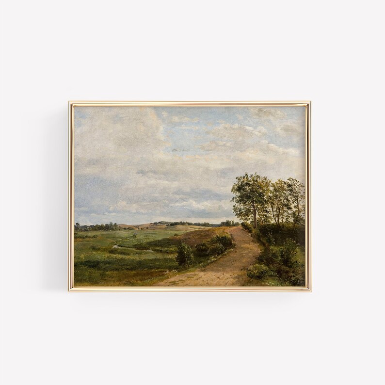 May include: A framed painting depicting a rural landscape with a winding dirt road leading through a field of green grass and trees. The sky is a light blue with fluffy white clouds.
