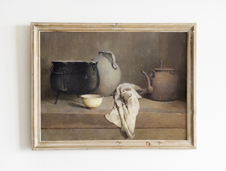 May include: A framed still life painting depicting a black cast iron pot, a white ceramic pitcher, a brown metal teapot, and a white ceramic bowl on a wooden table with a white cloth draped over the edge.