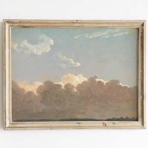 May include: A framed painting depicting a landscape with a cloudy sky. The clouds are a soft pink and white, with a hint of blue in the sky. The painting is in a simple, light wood frame.