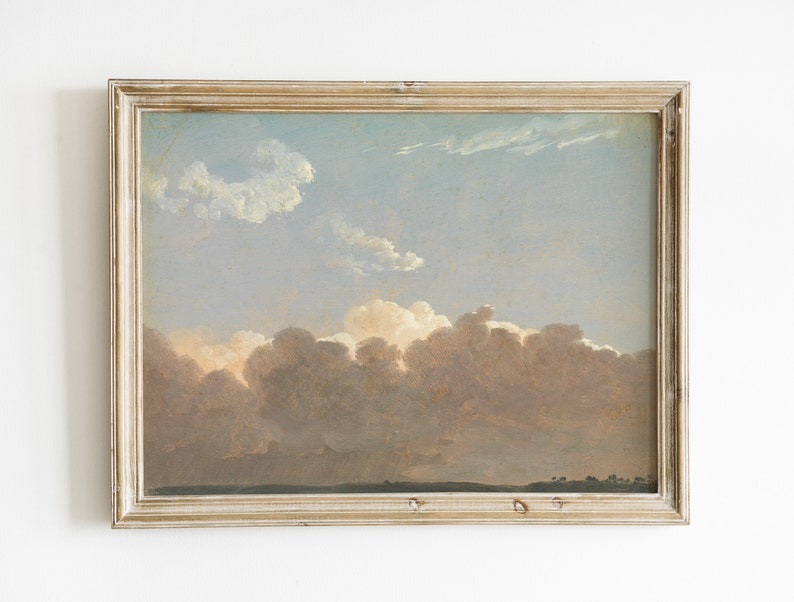May include: A framed painting depicting a landscape with a cloudy sky. The clouds are a soft pink and white, with a hint of blue in the sky. The painting is in a simple, light wood frame.