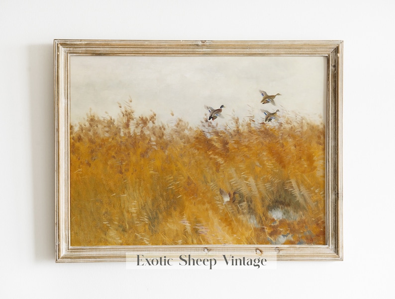 May include: A framed vintage painting of a field of tall, golden grass with three ducks flying over it. The painting has a light brown frame.