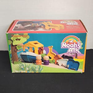May include: A colorful Noah's Ark toy set by Tupperware. The box features a yellow ark with a blue boat, a rainbow, and various animal figures. The box says "Noah's Ark Toy Set" and "Hours of Fun".