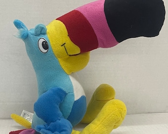 May include: A plush toucan toy with a large, colorful beak. The beak is black, pink, and red. The toucan's body is blue, yellow, and white.