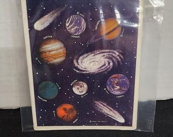 May include: Eight sheets of stickers featuring images of planets and celestial objects from NASA. The stickers include images of Jupiter, Venus, Saturn, Earth, Mars, Moon, Neptune, and a comet. The stickers are on a white background with a blue border.