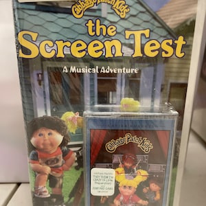 May include: A VHS tape of the Cabbage Patch Kids movie "The Screen Test: A Musical Adventure". The cover features a Cabbage Patch Kid doll wearing a blue shirt and holding a microphone. The tape is labeled "Sing For You" and features the song "They Think I'm Crazy (A Little Preparation)".