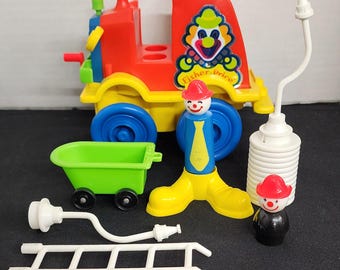 May include: A vintage Fisher-Price toy set featuring a red fire truck with a clown face on the side, a clown figure, a ladder, a hose, and a green wagon.