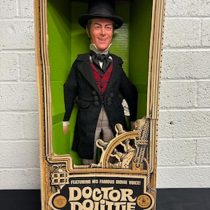May include: Vintage Doctor Dolittle pull-talking ring doll in original box. The doll is dressed in a black coat, red vest, and top hat. The box features the movie title and a ship's wheel design.