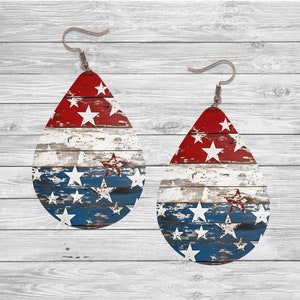 May include: A pair of teardrop-shaped earrings with a distressed woodgrain design and red, white, and blue stars. The earrings are made of wood and have a rustic look.