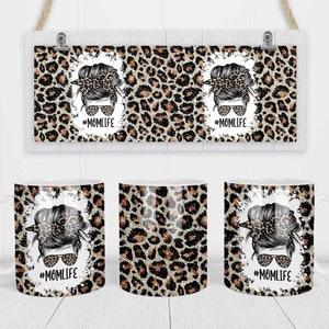 May include: Three white ceramic mugs with a leopard print design and a black and white illustration of a woman with a messy bun and sunglasses. The text "#MOMLIFE" is printed on each mug.